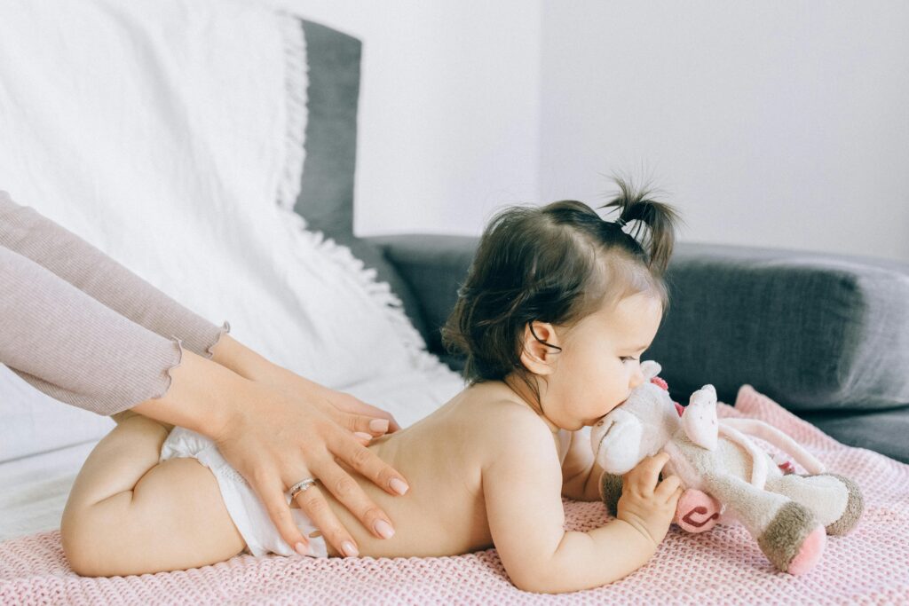 A serene moment of a baby receiving a gentle massage while holding a plush toy, epitomizing peace and comfort.