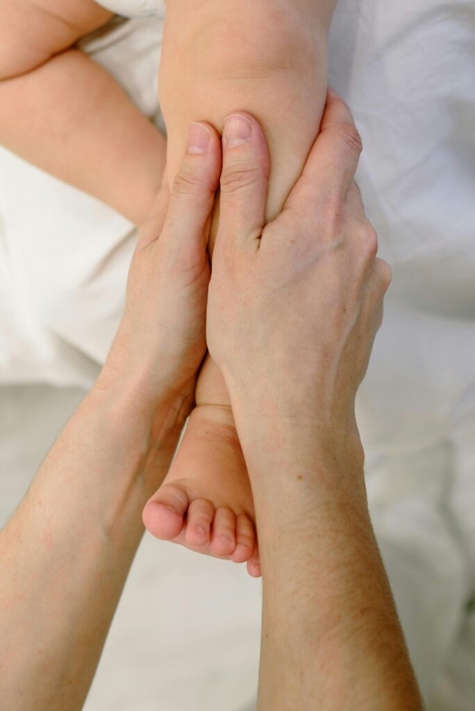 Gentle massage on a baby's leg by careful hands. Close-up of nurturing touch.